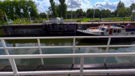Boat-passes-by-at-canal-with-open-sluice-gate-doors-fixed-wide-shot-in-Amsterdam