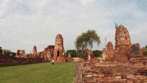 Toma-Panorámica-De-Templos-Históricos-En-Tailandia-Con-Turistas-Caminando-En-Un-Hermoso-Día