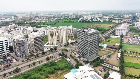 An-aerial-drone-camera-hovers-over-the-ring-road-in-Rajkot-City,-surrounded-by-skyscraper-buildings