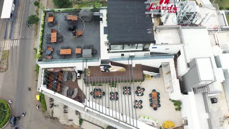 Aerial-view-of-a-terrace-restaurant-built-on-the-top-floor-of-a-high-rise-building,-aerial-drone-camera-shooting-in-a-Dutch-angle-from-top-to-bottom