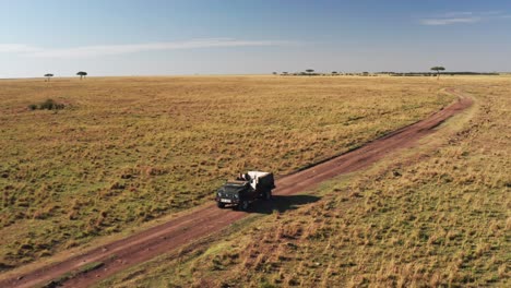 Aerial-drone-shot-of-Wildlife-Photographer-Driving-Safari-Vehicle-in-Maasai-Mara-National-Reserve-Savanna,-Kenya,-Africa-with-Beautiful-Landscape-Scenery,-Masai-Mara-North-Conservancy