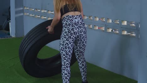 Bodybuilder-flipping-tires-in-sports-wear-at-a-gym