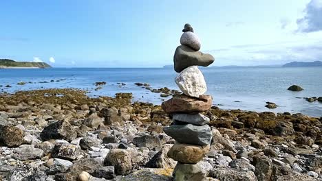 Balanced-stack-of-Zen-tower-stones-on-sunny-blue-sky-summer-beach-horizon