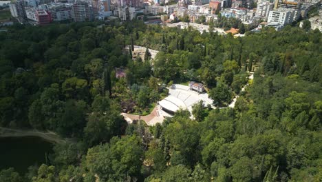 Drone-Aéreo-Disparado-Sobre-Un-Anfiteatro-En-Un-Parque-Urbano-Verde---Tirana,-Albania