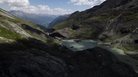 Alpine-lake-water-fed-directly-from-the-Pasterze-glacier-and-the-surrounding-mountains-in-the-Austrian-Alps,-Drone-shot