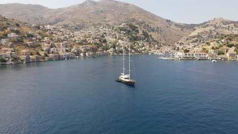 Aerial-orbit-around-a-large-sail-boat,-bay-of-Symi,-Greece,-scenic-panorama