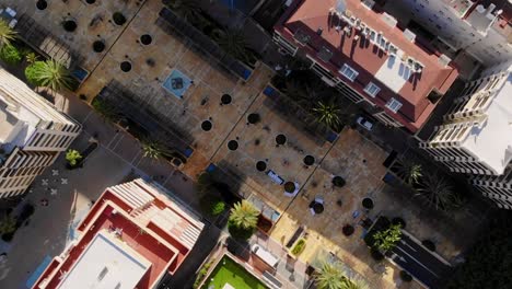 Drone-top-shot-turning-around-over-a-townsquare-in-Marbella,-Spain
