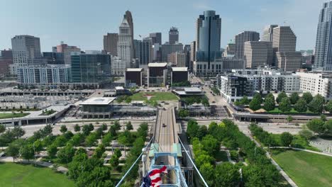 American-and-Ohio-flags-waving-on-bridge-in-front-of-Cincinnati,-OH-skyline