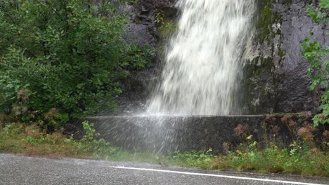 Roadside-waterfall-splashing-into-road-during-heavy-rain