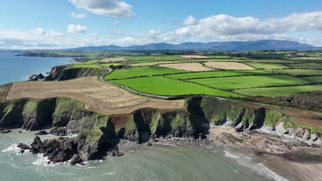 Aerial-Coast-of-Ireland-static-shot-along-The-Copper-Coast-Waterford-with-The-Comeragh-Mountain-Range-on-a-perfect-morning