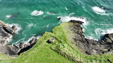 Coast-of-Ireland-drone-old-WW2-building-high-on-a-sea-cliff-at-Copper-Coast-Waterford-on-a-blustery-summer-day