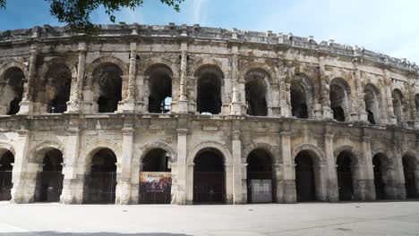 From-a-tree,-view-of-the-arenas-of-Nîmes-from-the-ground-in-the-middle-of-the-day-in-good-weather