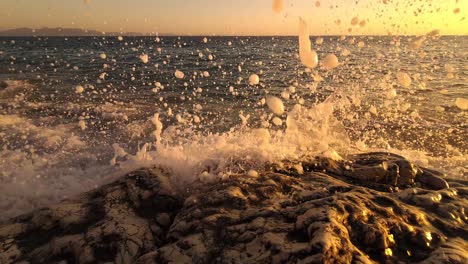 Sea-waves-splashing-and-foaming-on-carved-rock-at-golden-hour-of-twilight,-beautiful-romantic-spiritual-moments-on-shore-of-Mediterranean