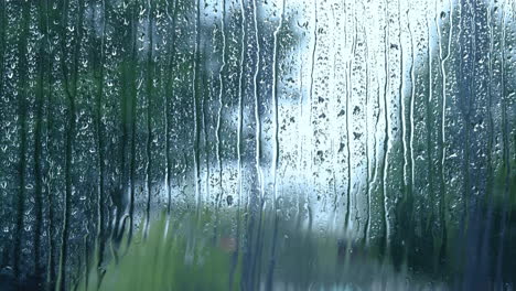 Closeup-wet-clear-window-glass-during-heavy-rain-against-blurred-city-view-in-a-rainy-day