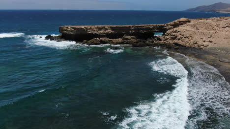 Vista-Aérea-En-Círculo-Sobre-La-Playa-De-La-Pared-En-La-Isla-De-Fuerteventura-En-Un-Día-Soleado,-Lugar-Popular-Para-Practicar-Surf-Y-Bodyboard