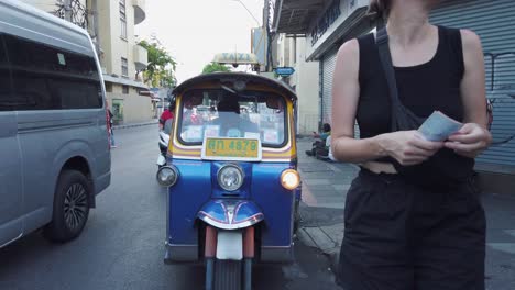 Kaukasische-Touristin-Bezahlt-Tuk-Tuk-Taxifahrer-Auf-Der-Bangkoker-Straße