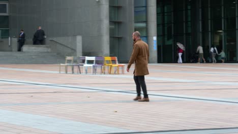 Un-Hombre-Adulto-Vestido-De-Forma-Elegante-E-Informal-Caminando-Fuera-Del-Edificio-Del-Parlamento-Europeo-En-Bruselas