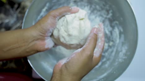 close-up-view-of-African-american-woman's-hands-kneading-pizza-dough-in-a-silver-pan-in-slow-motion