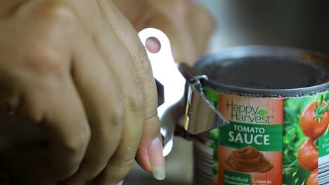 close-up-view-African-American-hand-is-opening-a-can-of-tomato-sauce-with-a-can-opener