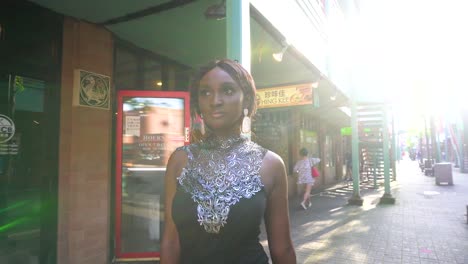 African-American-fashion-model-is-walking-along-Chinatown-square-in-Chicago-wearing-a-beautiful-trendy-stylish-black-dress-with-red-hand-bag