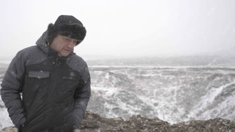 Middle-Age-Man-in-Warm-Winter-Clothes-Walking-on-Snowfall-in-Cold-Landscape-of-Iceland