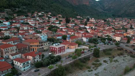 Dry-riverbed-and-iconic-red-orange-roofed-homes-vibrant-colors-in-leonidio,-greece,-aerial