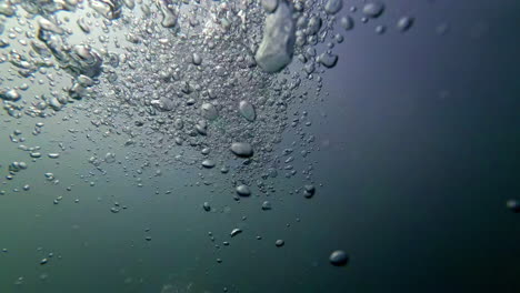 Cinematic-underwater-shot-of-air-bubbles-in-slow-motion-in-dark-waters