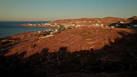 Drohnen-Trucking-Pfanne-Enthüllt-Zwischen-Hügeln-Versteckte-Küstenstadt-Auf-Syros,-Griechenland