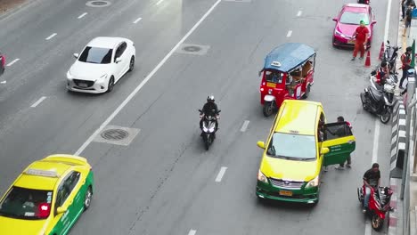 Thailändische-Taxis-Und-Rote-Tuk-Tuk-Fahren-Auf-Einer-Stark-Befahrenen-Straße-In-Bangkok-Mit-Ankommenden-Und-Abfliegenden-Passagieren,-Thailand