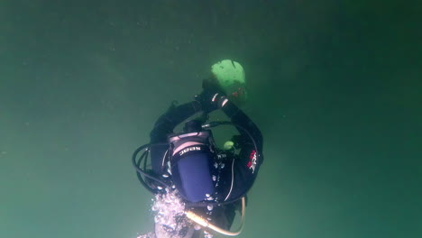 Cinematic-slow-motion-underwater-shot-of-a-scuba-diver-in-a-green-and-foggy-lake
