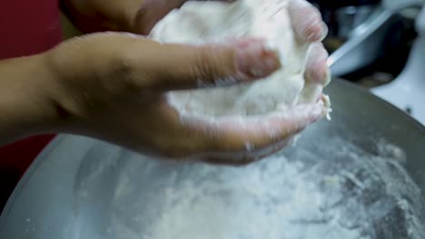 close-up-view-of-African-american-woman's-hands-kneading-pizza-dough-in-a-silver-pan-in-slow-motion