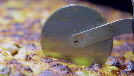 close-up-shot-of-a-pizza-cutter-cutting-delicious-tasty-home-made-gourmet-pizza