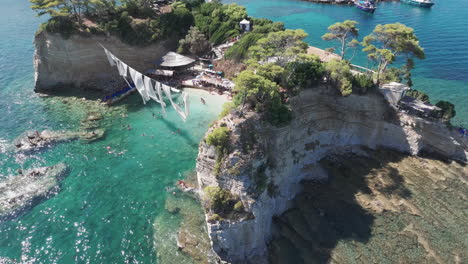 Aerial-View-of-Cameo-Island-Beach-With-Hanging-White-Fabrics,-Idyllic-Summer-Vacation-Location-of-Zakynthos,-Greece