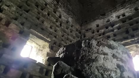 Inside-old-stone-Penmon-priory-dovecot-with-stone-wall-nesting-box-and-window-light