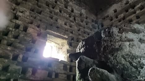 Inside-old-Penmon-priory-dovecot-with-stone-wall-nesting-box-looking-up-at-window-light