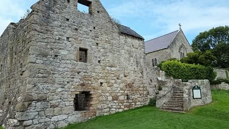 Exterior-of-rural-ancient-Penmon-stone-wall-priory-remains,-Wales-sightseeing-tourist-travel-destination