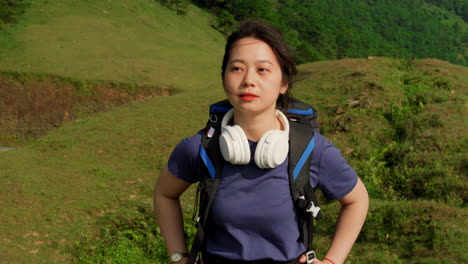close-up-portrait-slow-motion-of-young-asiatic-female-traveller-backpacker-with-modern-headphone-walking-in-mountains-hiking-trekking-path