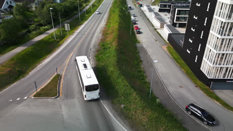 White-bus-drive-through-roundabout-in-Tromso-neigborhood,-aerial-tracking