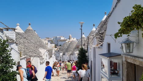 Überfüllte-Straße-Mit-Vielen-Touristen,-Die-Zwischen-Den-Trulli-Häusern-Mit-Konischen-Dächern-In-Alberobello,-Apulien,-Italien,-Spazieren