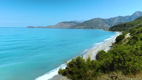 Green-and-blue-panorama-of-beautiful-coastline-in-Albania,-Olive-trees,-hills-and-mountains-on-amazing-bay-with-white-beaches-and-turquoise-sea-water