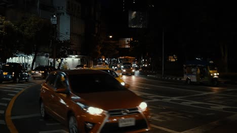 Cars,-taxi,-bus,-scooter-passing-by-at-nighttime-in-Bangkok,-Thailand-in-slow-motion