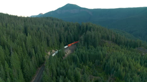 Aerial-shot-of-two-train-engines-pushing-a-long-line-of-freight-cars-through-a-high-mountain-pass