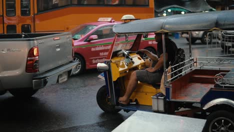 Tuk-Tuk-taxi-at-a-rainy-day-in-the-city-of-Bangkok,-Thailand-driving-through-the-street