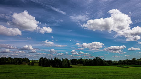 White-cumulus-clouds-pass-in-a-blue-sky-over-a-green-landscape