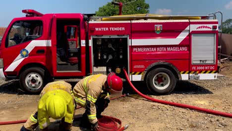 Feuerwehrleute-Rollen-Die-Wasserschläuche-Auf,-Nachdem-Ein-Feuer-Gelöscht-Wurde