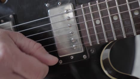 A-close-up-image-of-a-guitarist's-right-hand-picking-the-strings-on-a-black-335-style-electric-guitar