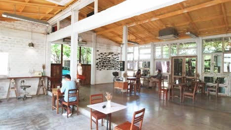 Toma-Panorámica-Interior-De-Un-Café-Tailandés-En-Bangkok-Con-Gente-Sentada-Tomando-Café,-Tailandia