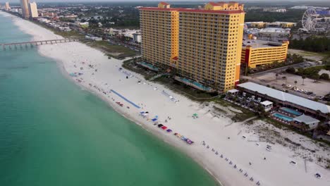 Aerial-view-of-Calypso-resort-and-towers-on-the-beach-of-Panama-city-beach,-Aerial-view-beachfront-resort-hotel-with-skywheel-at-pier-park-in-background-Gulf-of-Mexico-Aerial-view-during-morning-dawn