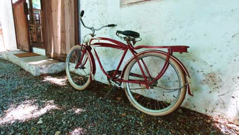 Classic-Red-Bicycle-Resting-Against-a-White-Wall-Next-to-a-Sliding-Door-Entrance-to-a-Cafe-in-Bangkok,-Thailand