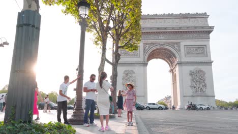 Tourists-Posing-for-Photos-at-Arc-de-Triomphe-in-Paris-during-Sunset:-Captured-Moments,-Golden-Hour-Atmosphere,-Iconic-French-Landmark,-Evening-Light